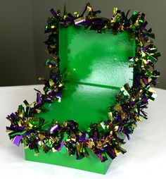 a green box with purple and gold tinsel on it