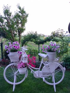 two white bicycles with flower pots on the back