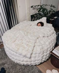 a woman is laying in a bed made out of fluffy white blankets on the floor