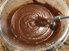 a glass bowl filled with chocolate and whisk