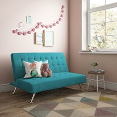 a living room with pink walls and green futon