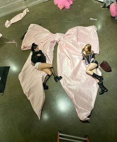 two women laying on the ground covered in pink sheets