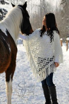 a woman standing next to a horse in the snow