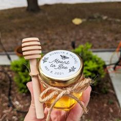 a hand holding a jar of honey and a wooden stick