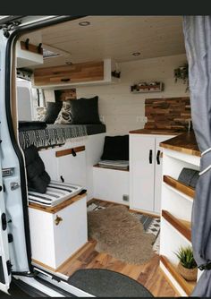 the interior of a camper van with wood flooring and white cabinets, including drawers