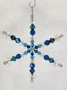 a snowflake ornament with blue and clear beads hanging from a hook