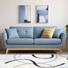 a living room with two paintings on the wall and a blue couch in front of it