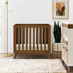 a baby crib in the corner of a room with a rug and potted plant