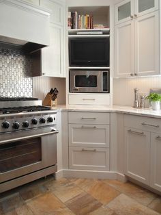 a kitchen with white cabinets and stainless steel stove top oven in the center, surrounded by tiled flooring