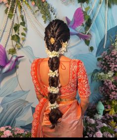 a woman with braids and flowers in her hair is standing against a floral wall