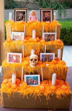 a cake made to look like a box with pictures and candles on it that is decorated in orange shredded paper