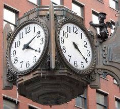 a large clock mounted to the side of a building with statues on it's sides