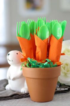 there are plastic utensils in a flower pot with green and orange decorations on it