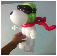 the balloon dog is wearing sunglasses and a red scarf on it's head, while being held by a hand