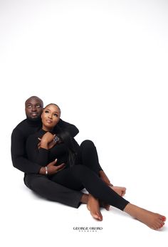 a man and woman sitting on the ground posing for a photo with their arms around each other