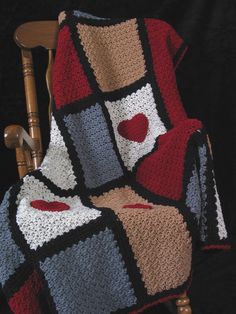 a crocheted blanket on a chair with a heart in the center and two hearts at the bottom