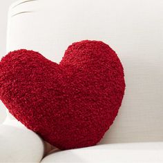 a red heart shaped pillow sitting on top of a white couch