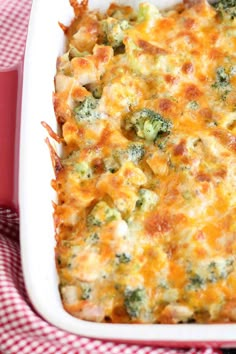 a casserole dish with broccoli and cheese in it on a checkered cloth