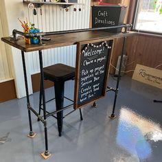 a bar with two stools and a chalkboard sign