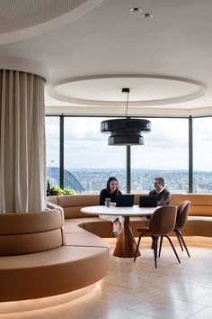 two people sitting at a table in front of large windows