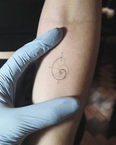 a person with a glove on their arm is holding a tattoo that has a spiral design on it