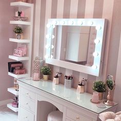 a white vanity with lighted mirror and stool in a pink room next to striped wallpaper