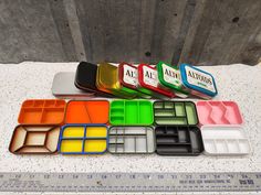 there are many different colored trays next to each other on the table with a ruler