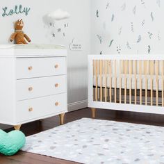 a baby's room with a crib, dresser and teddy bear on the floor