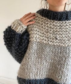 a woman is wearing a sweater made out of knitted yarn and has her hands on the shoulder