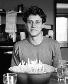 a man sitting in front of a cake with candles on it