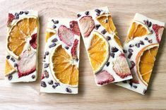 four slices of fruit and chocolate on top of a wooden table with white frosting