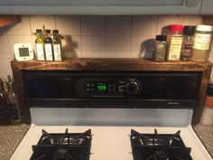 a stove top oven sitting inside of a kitchen next to a shelf filled with spices