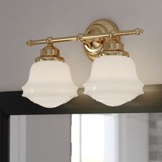 two light bathroom fixture with white glass shades on the top and gold trimmings