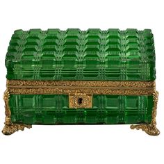 a green glass box with gold trimmings on the top and bottom, sitting in front of a white background