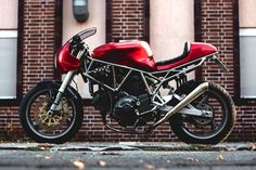 a red motorcycle parked in front of a brick building