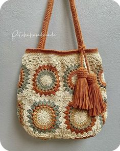 a crocheted handbag hanging on the wall with tassels and fringe