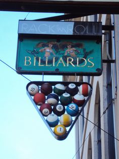 billiards sign hanging from the side of a building with pool balls on it