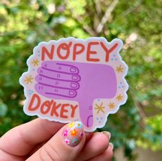 a hand holding up a sticker that says nopey dokie