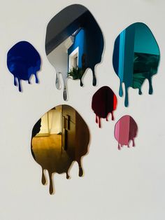 four different colored mirrors hanging on the wall