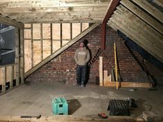 a man standing in an attic with exposed walls