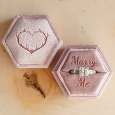 two wedding rings in pink velvet boxes with the words marry me engraved on them,