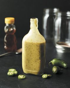 a bottle filled with mustard sitting on top of a table next to some green peppers