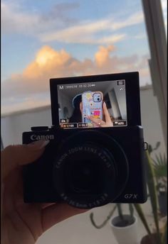 a person holding up a camera to take a photo with the sky in the background