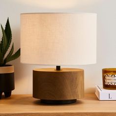 a wooden table with a lamp on it and some books next to it, along with a potted plant