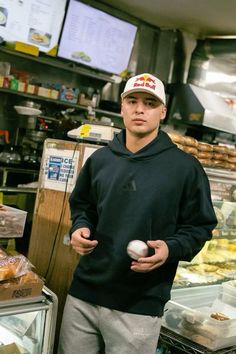 a man standing in front of a counter holding a ball and some doughnuts