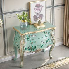 a green and gold painted chest with flowers on top