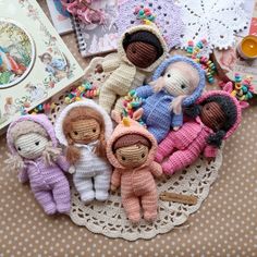 small crocheted dolls sitting on top of a doily next to a book