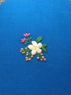 a piece of blue fabric with flowers embroidered on the front and side, sitting next to a pair of scissors