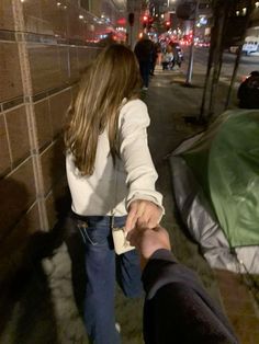 two people holding hands walking down the street