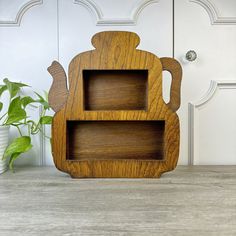 a wooden shelf sitting on top of a table next to a potted green plant